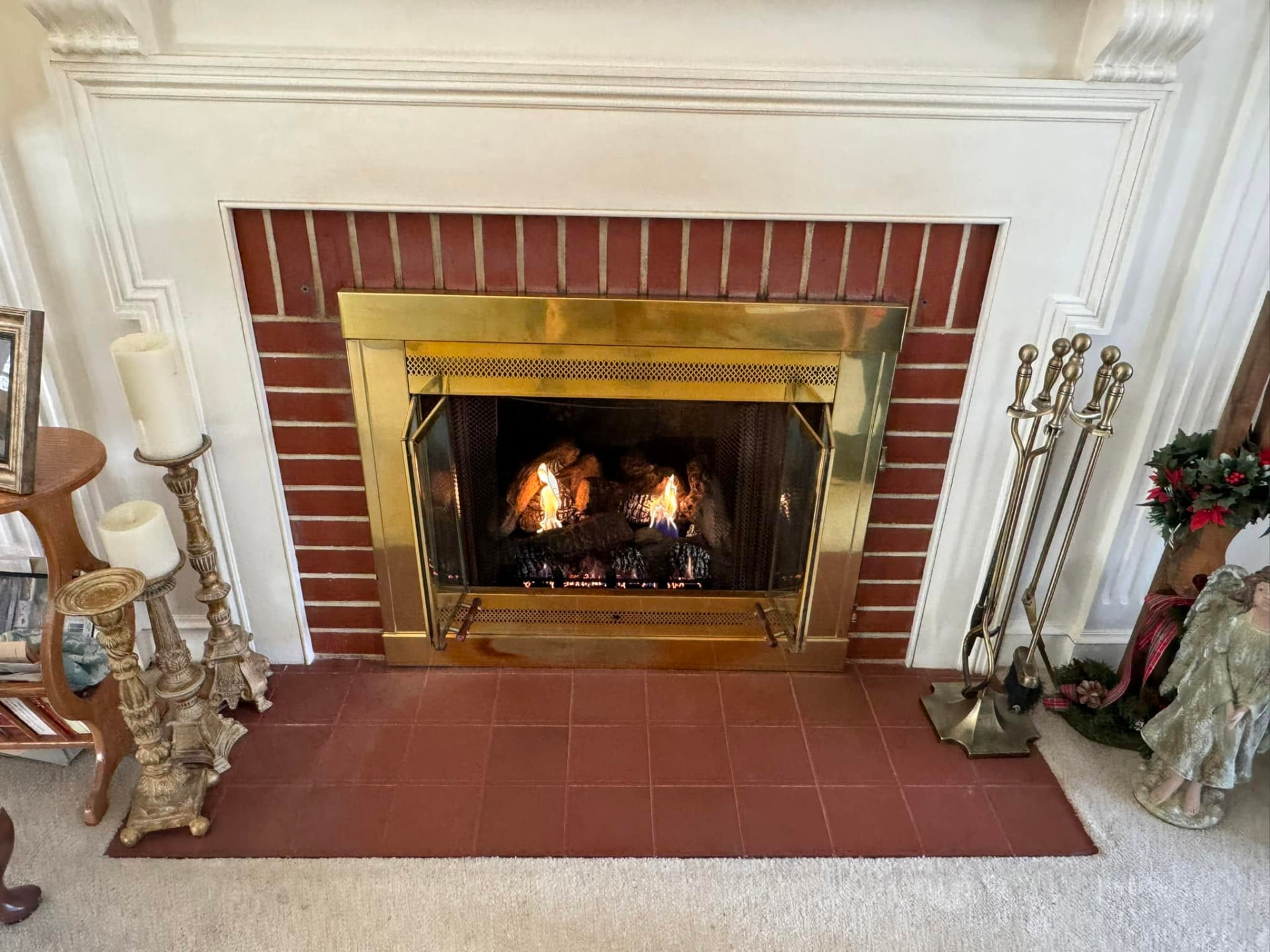 Gas fireplace logs burning behind a brass fireplace surround after service