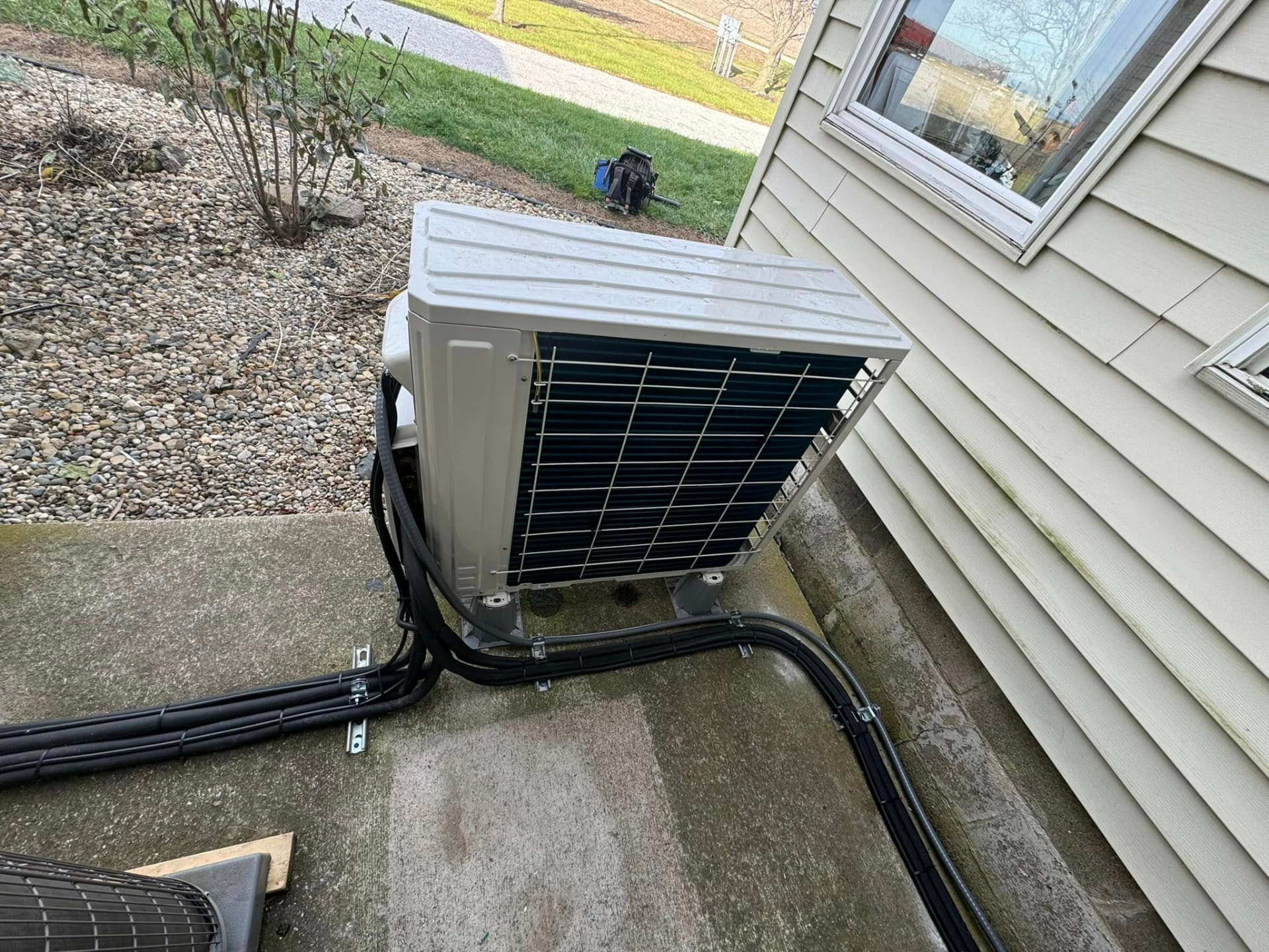 Newly installed ductless mini-split outdoor unit with neatly routed line set on a concrete pad