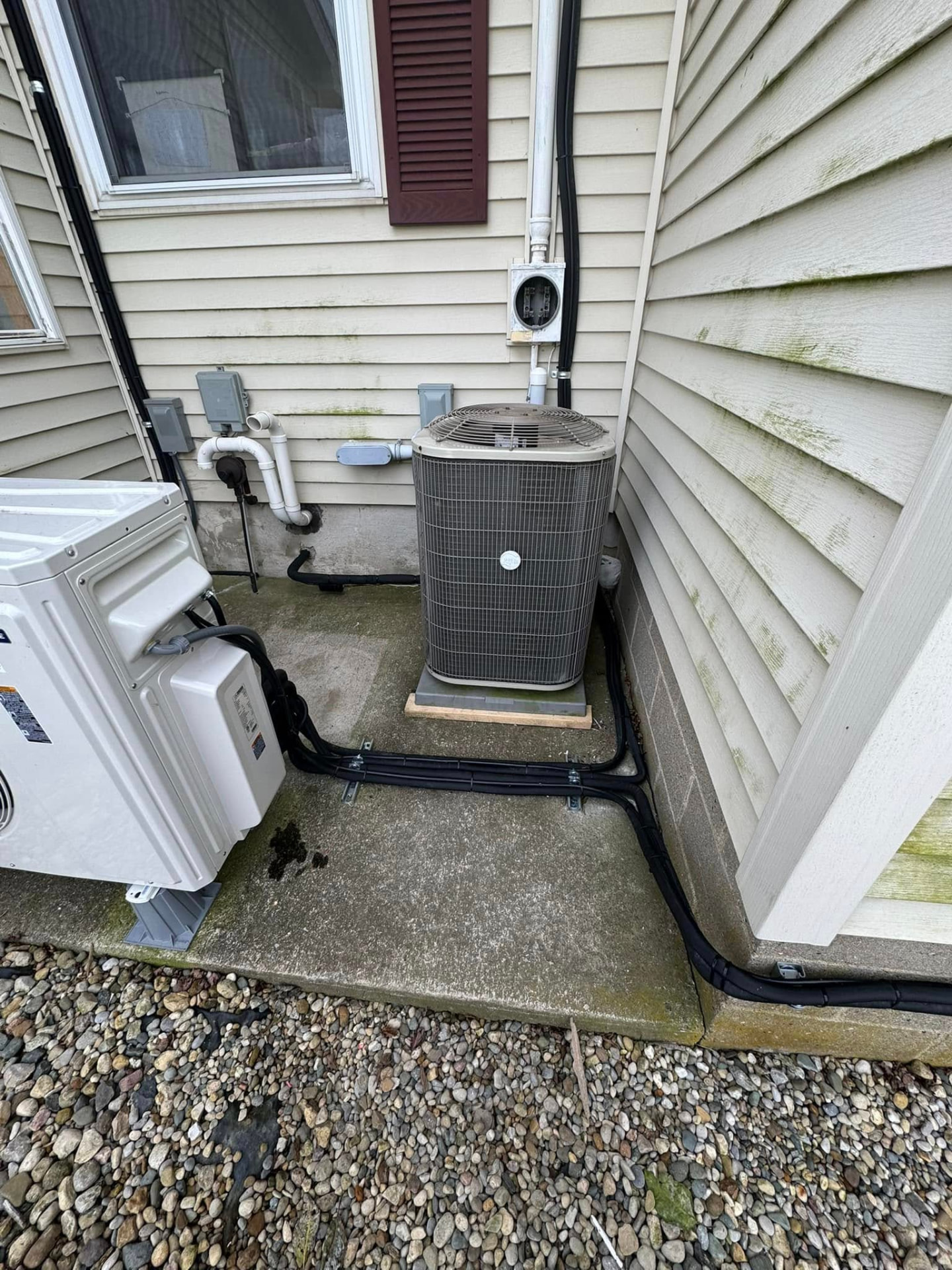 Ductless mini-split condenser installed beside a central AC unit at an Indiana home